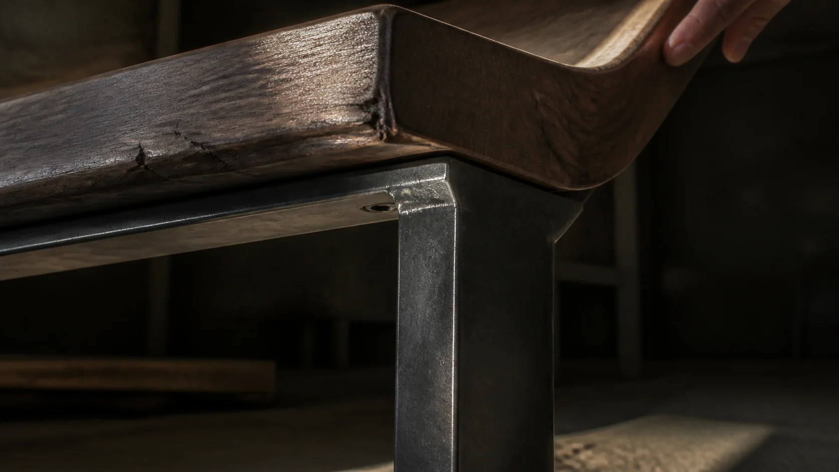 Close detail of a walnut tabletop meeting its blackened-steel support